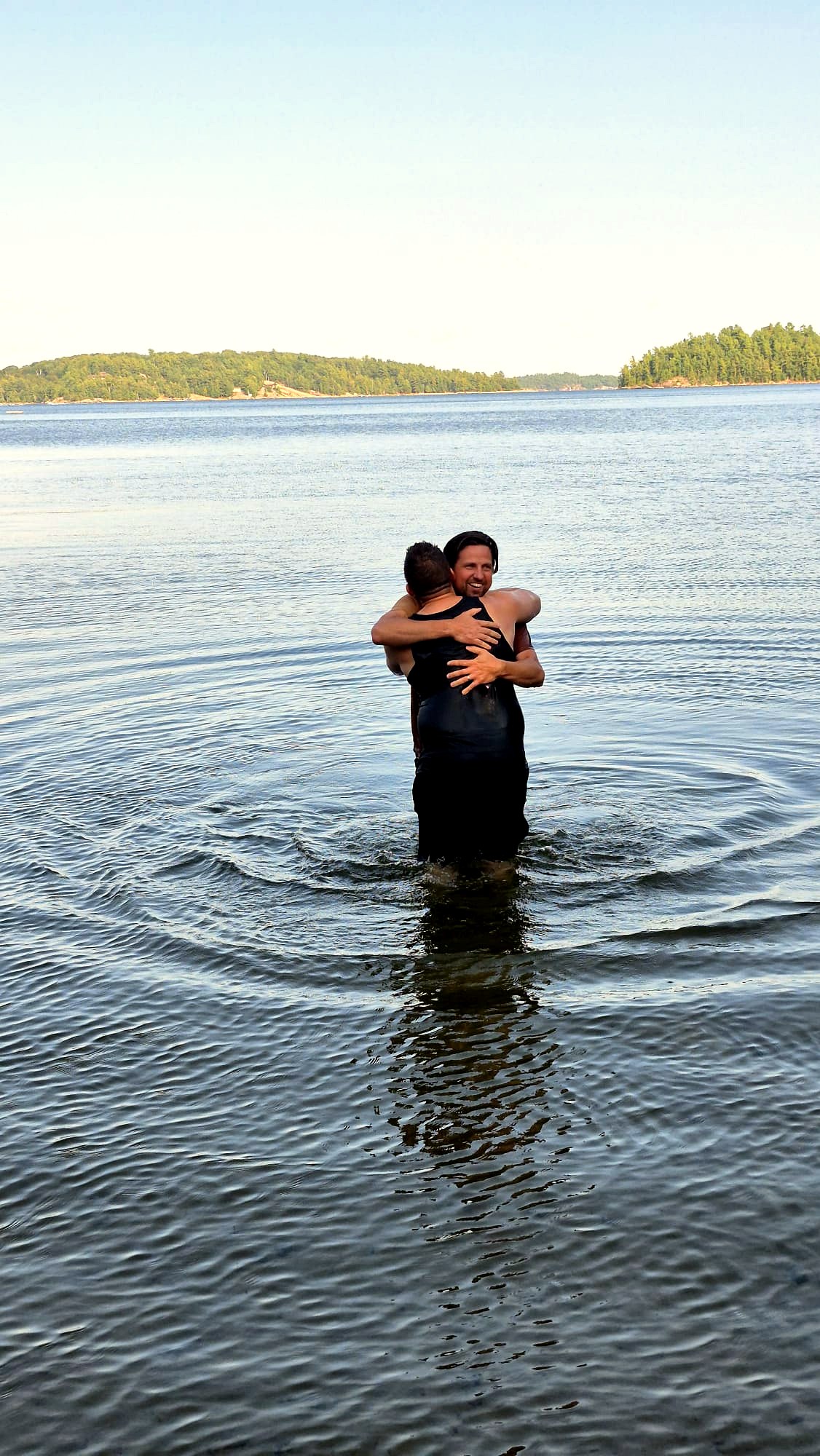 Baptism in the lake — two men embracing in the water