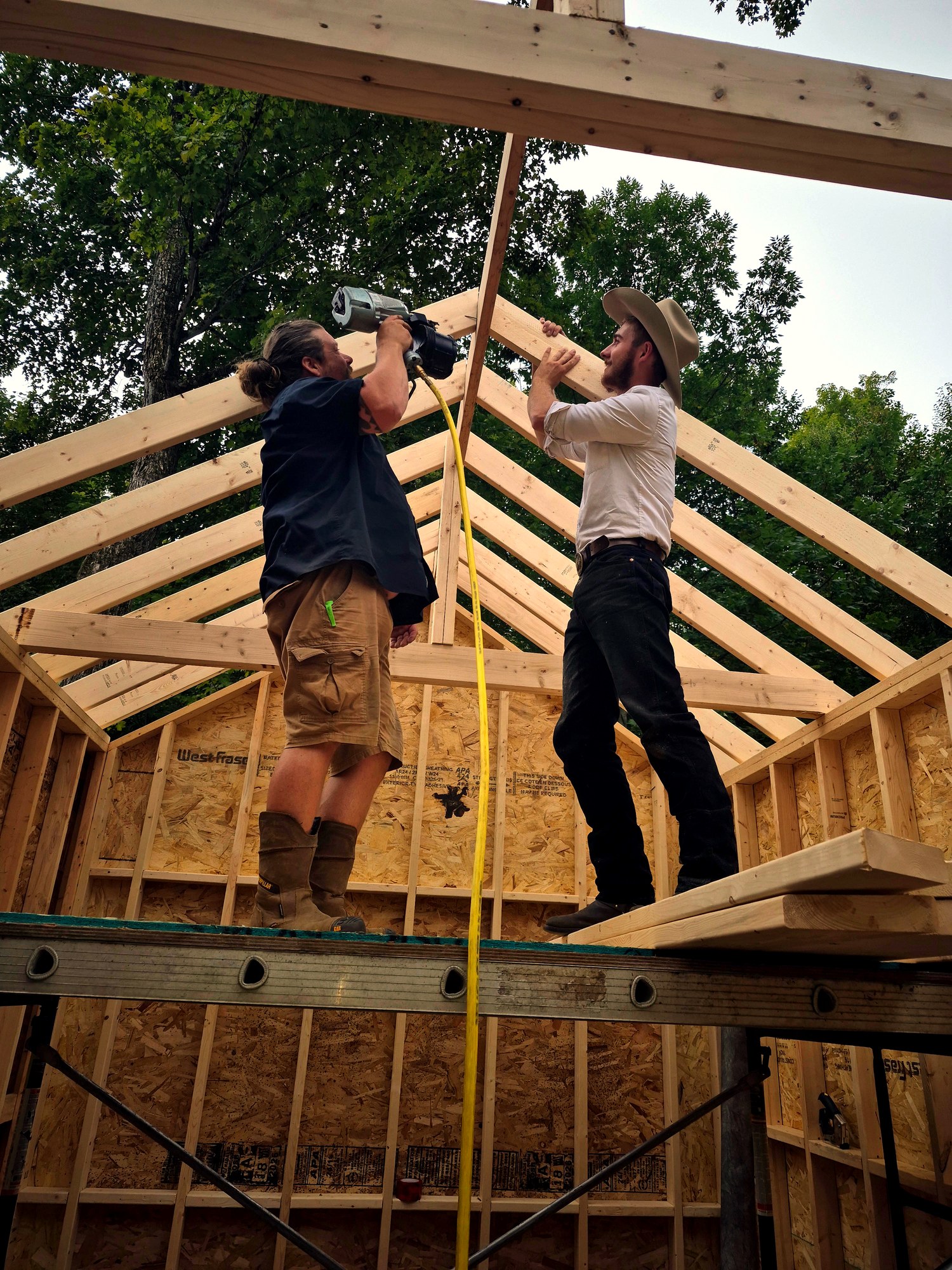 Two men framing a wooden roof structure